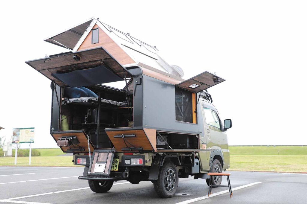 Custom kei truck camper conversion with A-frame pop-up roof and rustic wooden accents parked outdoors